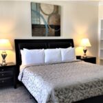 Furnished bedroom with king bed, dark headboard and matching nightstands