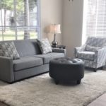 Grey sofa and round ottoman in a furnished living room